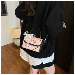 Rear view of a model wearing a pink crossbody bag with heart prints and lace details