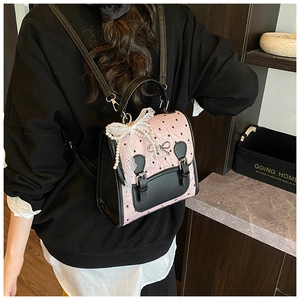 Détail du sac à dos rose et noir avec nœuds en dentelle et pendentif en perles