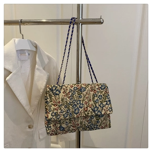 Close-up of vintage floral jacquard pattern and metal chain strap on textured handbag