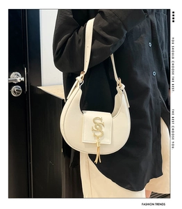 Detalle de bolso hobo de cuero blanco con hebilla en S dorada y elegante borla de flecos