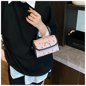 Detail of pink wrinkled mini handbag with black bow prints and silver hardware
