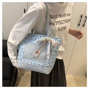 Detail view of light blue quilted tote bag with silk scarf accent and front pocket