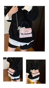 Detailed view of pink heart-print handbag with delicate lace bow and pearl chain charm