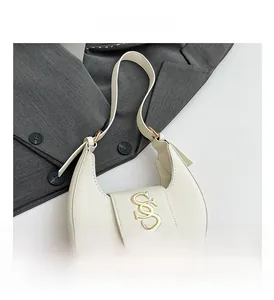 Primer plano del bolso hobo blanco con logo dorado y una americana gris elegante