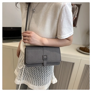 Détail du sac bandoulière en denim gris avec tissu texturé et rabat rectangulaire