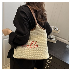 Detail of Hello embroidery on beige woven tote bag with brown leather shoulder straps