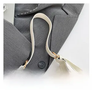 Detalle de la correa de cuero blanco con herrajes dorados del bolso de media luna