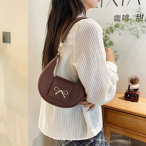 Borsa a spalla marrone a mezzaluna con fibbia a fiocco dorata indossata da modella