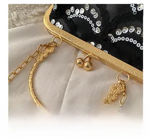 Detail of black lace evening bag featuring golden floral handle and sequins on lace