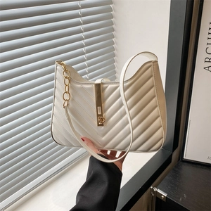 Minimalist beige quilted shoulder bag with gold clasp and chain detail in sunlight