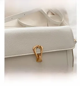 Detailed close-up of white lychee leather texture and golden metal lock on the shoulder bag