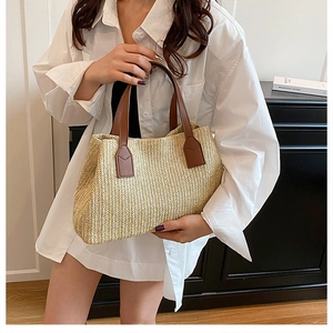 Detail shot of a woman holding a stylish Korean-style straw woven handbag in beige.