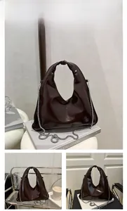 Detail of coffee brown patent leather handbag with silver chain and glossy finish