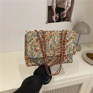 Ethnic floral underarm bag with gold chain strap in minimalist Nordic interior setting