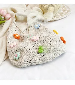 Detail of handmade crochet tote bag featuring colorful 3D knit flowers on cream fabric
