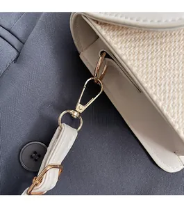 Detailed macro view of cream crossbody bag with woven texture and gold metal buckle