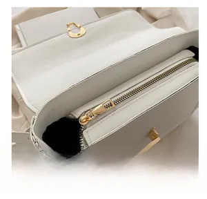 Close-up of white lychee leather texture with gold metal zipper and lock detail