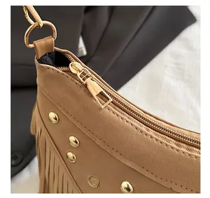 Detail shot of the golden zipper closure and metallic rivets on brown tassel bag