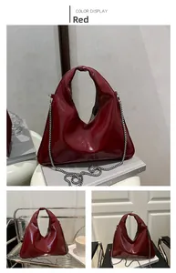 Detail of burgundy glossy patent leather underarm bag with silver chain strap