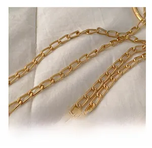 Close-up of polished golden metal chain strap featuring oval links on a fabric surface