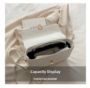 Detail view of white pebbled leather bag interior with gold buckle and daily essentials