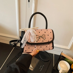 Pink pleated shoulder bag with black hearts, pearl charm, and lace bow detail