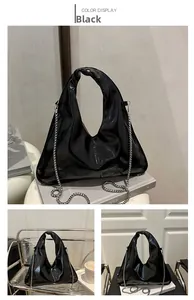 Detail of black patent leather handbag with triangle shape and knot handle accents