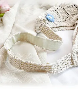 Detail of hand-woven shoulder bag handle with blue crochet flower and beige lining