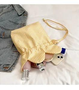 Macro shot of yellow plaid drawstring bag filled with cosmetics and mobile phone