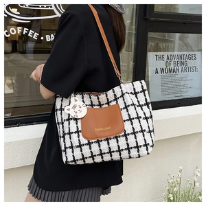 Detail of checkered tweed tote bag with brown leather pocket and cute cat pendant charm