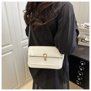 Detail of white litchi texture shoulder bag featuring a gold horseshoe metal buckle