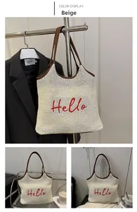 Detail of beige woven tote bag featuring red Hello embroidery and brown leather trim