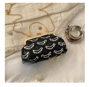 Macro shot of black sequin dinner bag with gold clasp, chain strap and floral handle