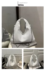 Detail view of white triangular underarm bag with silver chain strap and smooth finish