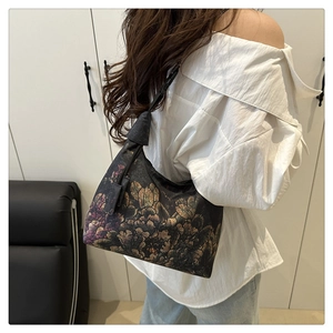 Detail of vintage floral pattern on a black shoulder hobo bag worn by a model
