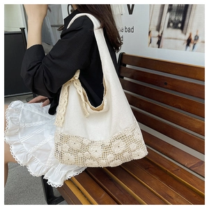 Close-up shot of a white canvas shoulder bag with intricate hollow lace flower detail