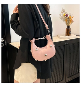 Rosa halbmondförmige Schultertasche mit silbernen Nieten in Lifestyle-Umgebung