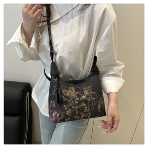 Detail of vintage floral embroidery bucket bag with adjustable nylon strap worn by model