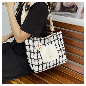 Detail of checkered tweed tote bag featuring cream leather pocket and cute tiger charm