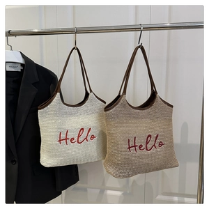 Detailed close-up of woven tote bag with red Hello embroidery and leather trim handles