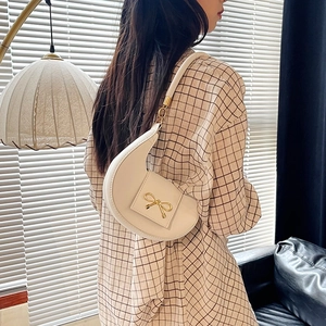 Elegante borsa a spalla crema a mezzaluna con fiocco dorato e finitura liscia moderna