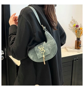 Bolso de hombro verde en forma de luna con logo S dorado y borlas de metal detalle