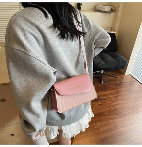 Detail of pink patchwork crossbody bag with textured fabric and leather flap shown on model