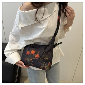Lifestyle view of a navy crossbody bucket bag with orange persimmon embroidery detail