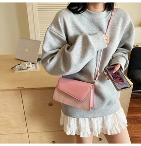 Detail of pink leather and woven crossbody bag showing the fashion logo and metal clasp