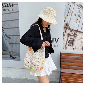 Outdoor shot of a cream hollow-out crochet tote bag with colorful 3D floral accents
