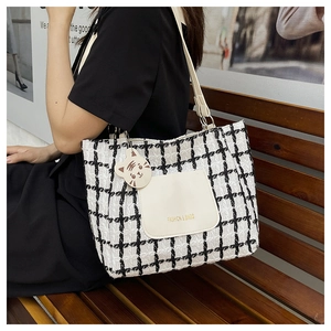 Detail of checkered tweed tote bag featuring front leather pocket and cute cat charm