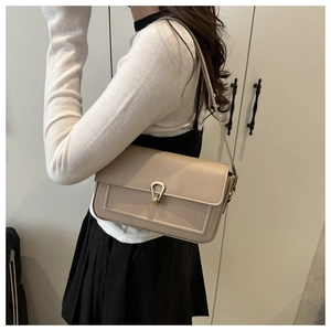 Detail of beige rectangular flap bag featuring a golden teardrop twist lock and leather texture
