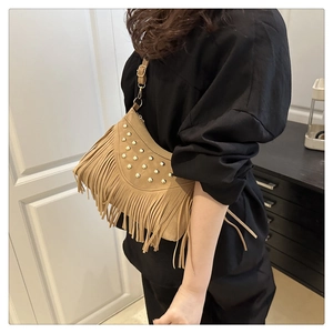 Detail of vintage camel suede crossbody bag featuring gold studs and long fringe tassels