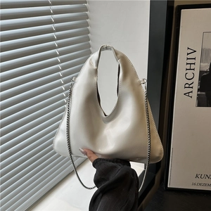 White minimalist triangle hobo bag with a sleek silver chain strap shown in a modern setting